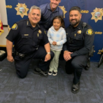 Police posing with Family Justice Center client's kid at a graduation event.